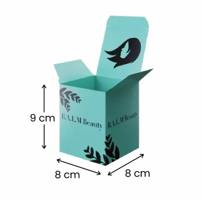 8 x 8 x 9 cm Caja de envío verde azulado con tapa abierta y marca personalizada; incluye el logotipo de una pluma negra y "B.A.L.M Beauty" con motivos decorativos de hojas; representa las opciones de envasado del producto.