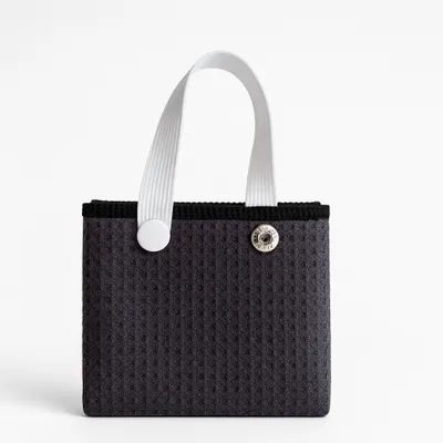 Close-up of a custom golf towel with a grommet and hook on orange fabric, indicative of premium towels online.